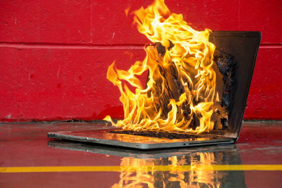 Brennender Laptop als Symbol für einen gravierenden IT-Ausfall und die Notwendigkeit vorbeugender IT-Optimierung.